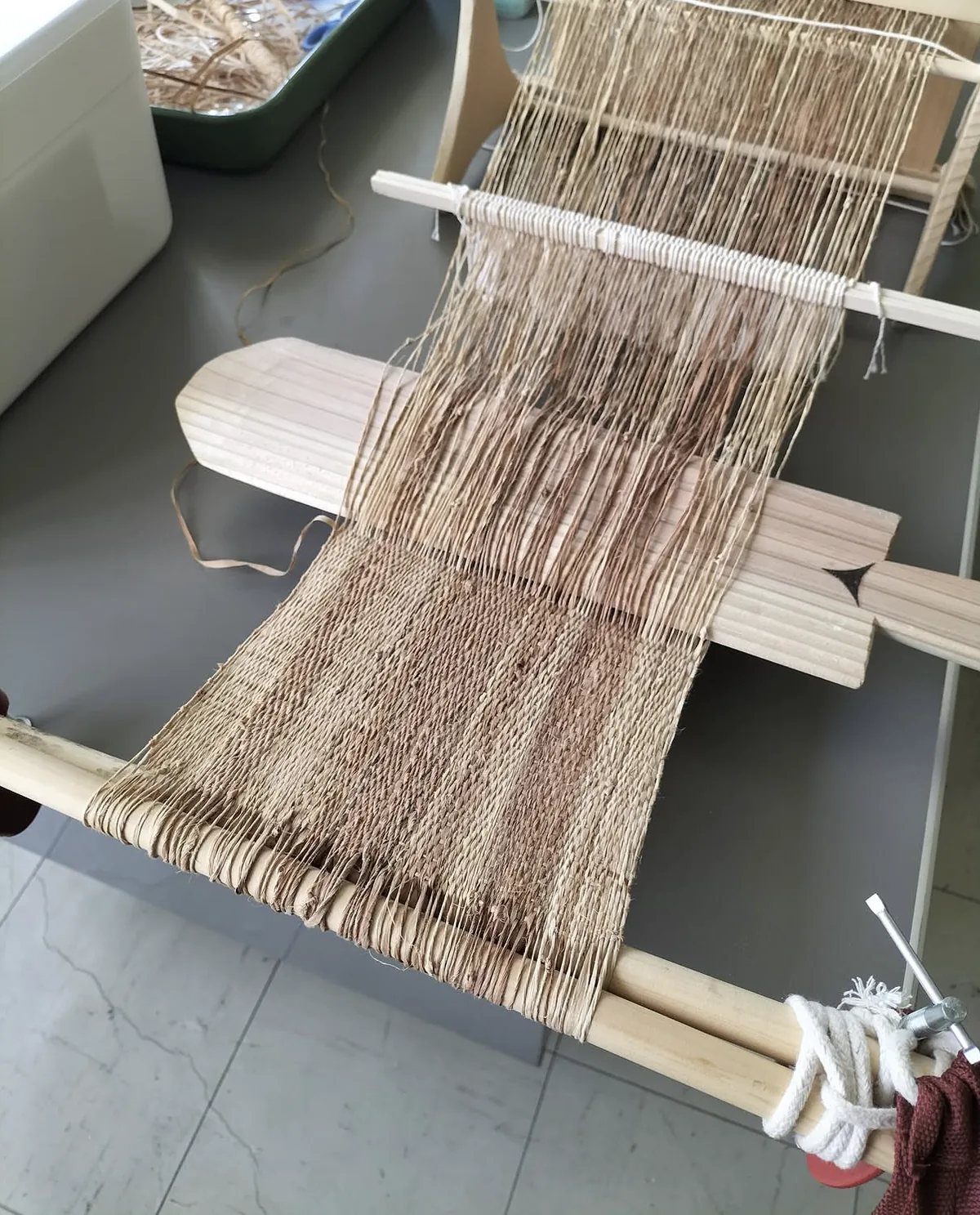 アットゥシを織る様子。木の繊維から布ができていく途中の織り機。